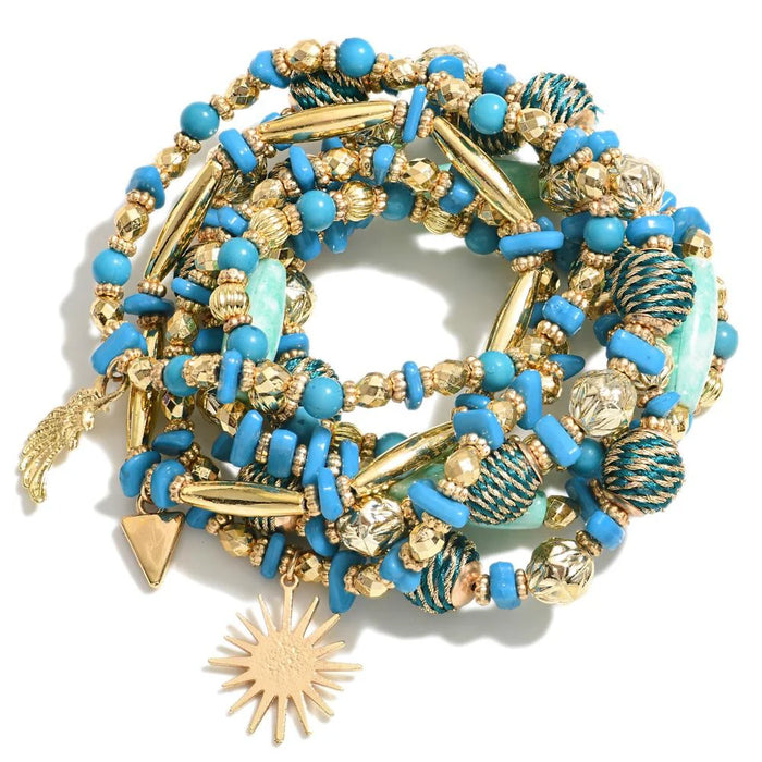 Blue Set of Nine Beaded Stretch Bracelets Featuring Gold Tones And Metallic Rope Wrapped Beads With Wing & Sun Charms