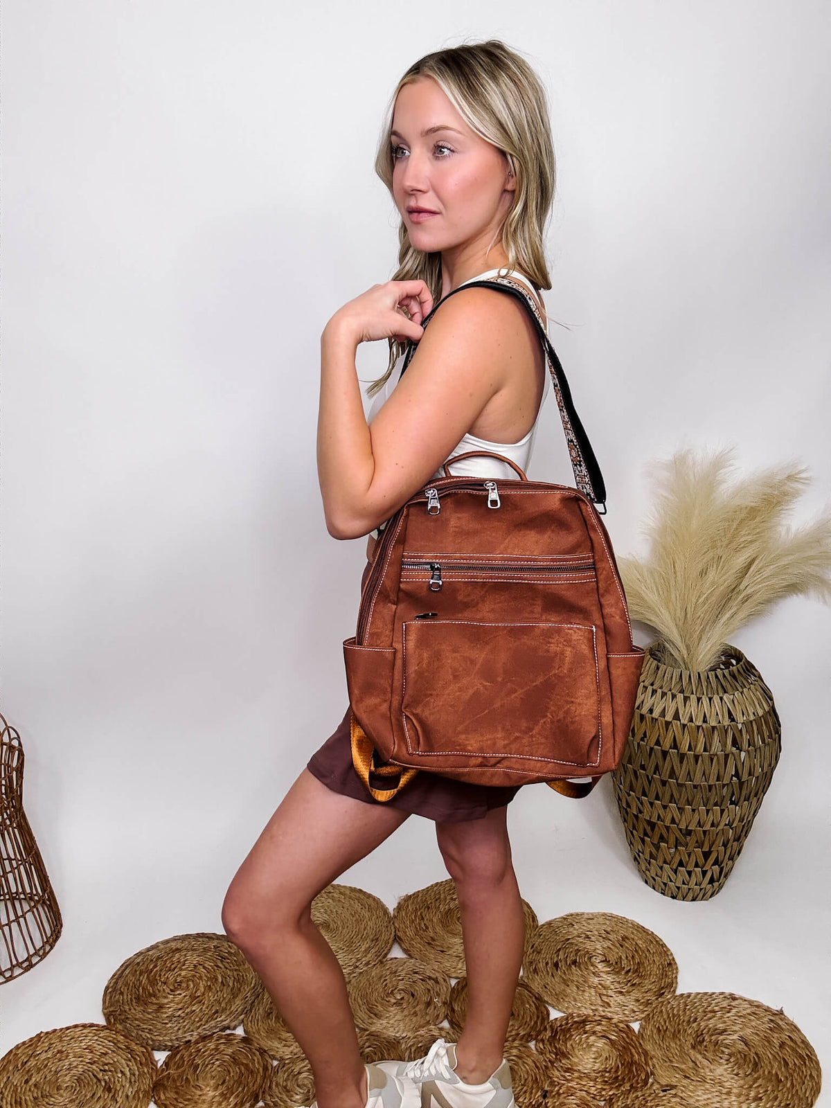 Brown Acid Washed PU Leather Backpack With Boho Strap and Matching Wristlet Full Zipper Closure Main Compartment: 2 Zipper / 2 Stash Pockets & Tablet Pocket Two Front Zipper Pockets Two Side Pockets One Zipper Pocket on Bag Back Removable Guitar Carry Strap (23"-46"L) Adjustable Backpack Straps Wristlet Approximately 7"W X 5"T Bag Body 14"T X11" W X 4.5D Material: Canvas Textured PU Leather