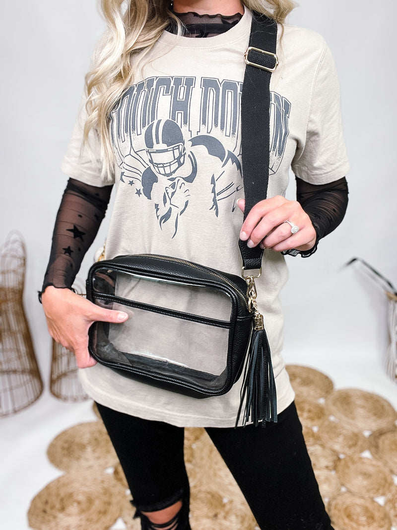 Game Day Bag Clear with Black and Gold Accents Cross PU Cross Body Bag Leather Walls and Trim Detachable Black Leather Tassel Full Zipper Closure One Outer Open Pocket Detachable Canvas Strap Approximately 6.5" T x 10" L x 2.5" W Strap Drop 15" - 24" L