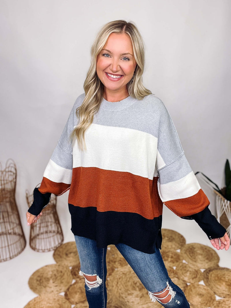 Neutral Grey, White, Rusty Brown, Black Colorblock Stripe Knit Sweater Oversized Fit Side Slits Ribbed Cuffs and Bottom Band Round Hem Neckline Soft and Stretchy Oversized Fit 50% Acrylic, 230% Nylon, 20% Polyester