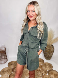 She and Sky Fall Utility Romper Washed Olive Long Sleeve Romper Button Up Front Button Roll Up Cuffs Functioning Waist Drawstring Button Shoulder Details Side Dips Soft Flowy Material Relaxed Fit 100% Rayon