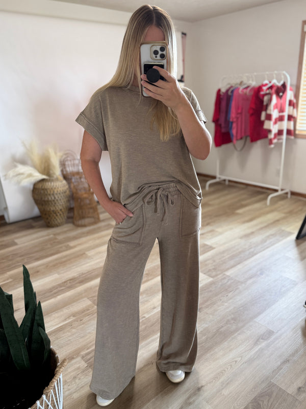 Woman’s matching two-piece lounge set consisting of a short-sleeve t-shirt and wide-leg drawstring pants in a taupe color.