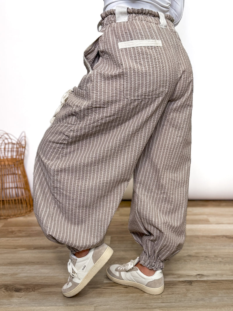Stay comfy and stylish in these coco and white striped jogger pants. Relaxed fit, elastic drawstring waist, pockets, and cuffs. Perfect neutral joggers for fall outfits.
