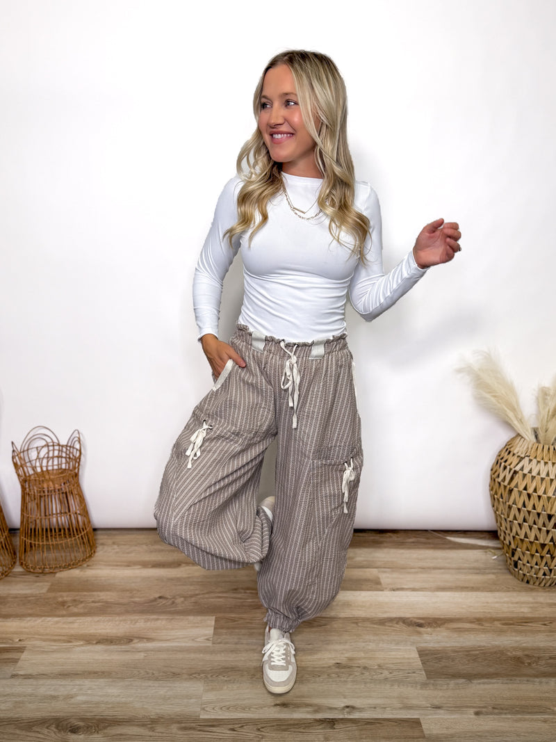 Stay comfy and stylish in these coco and white striped jogger pants. Relaxed fit, elastic drawstring waist, pockets, and cuffs. Perfect neutral joggers for fall outfits.