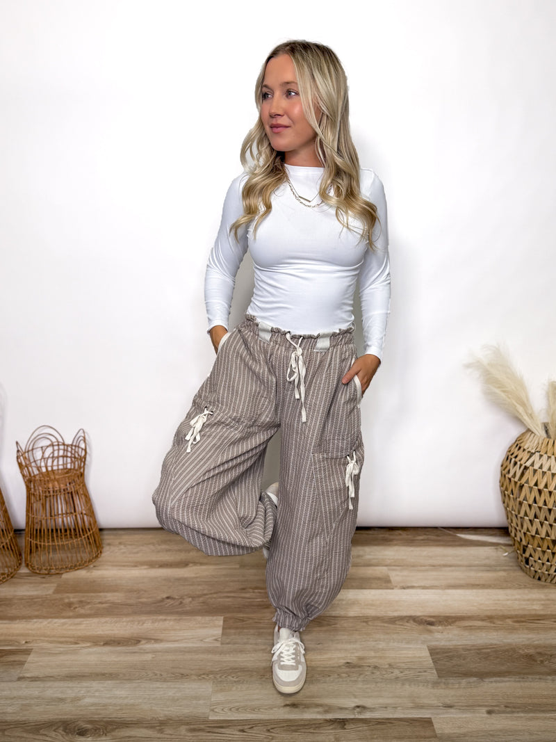 Stay comfy and stylish in these coco and white striped jogger pants. Relaxed fit, elastic drawstring waist, pockets, and cuffs. Perfect neutral joggers for fall outfits.