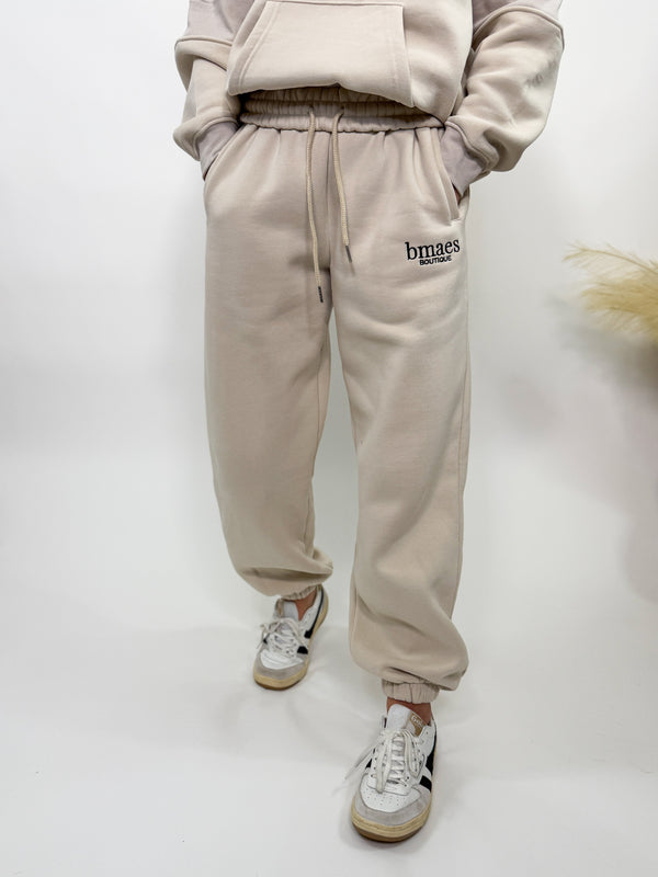 Cream fleece-lined luxury lounge Bmaes joggers with elastic drawstring waistband, deep pockets, and elastic ankle cuffs. Perfect for lounging or pairing with the matching hoodie for a chic, cozy set from Bmaes Boutique.