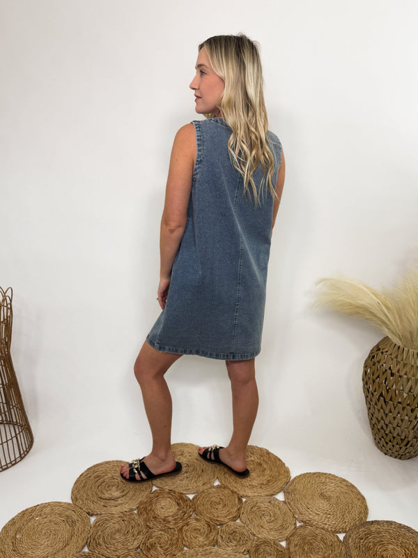 Sleeveless denim mini dress with a gold-colored button-down front, functional pockets, and a relaxed fit—perfect for spring and summer styling.
