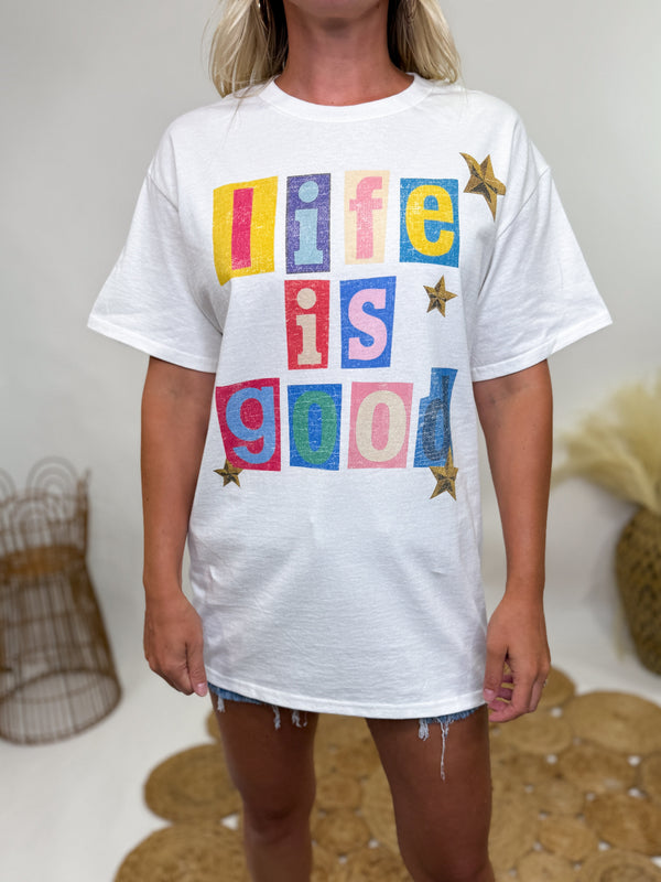 White oversized t-shirt with colorful “Life is Good” block lettering and stars