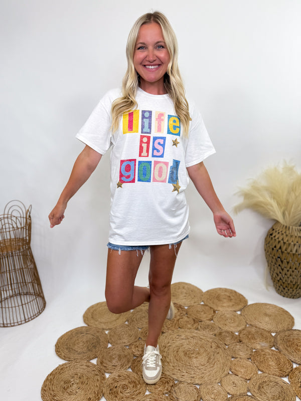 White oversized t-shirt with colorful “Life is Good” block lettering and stars