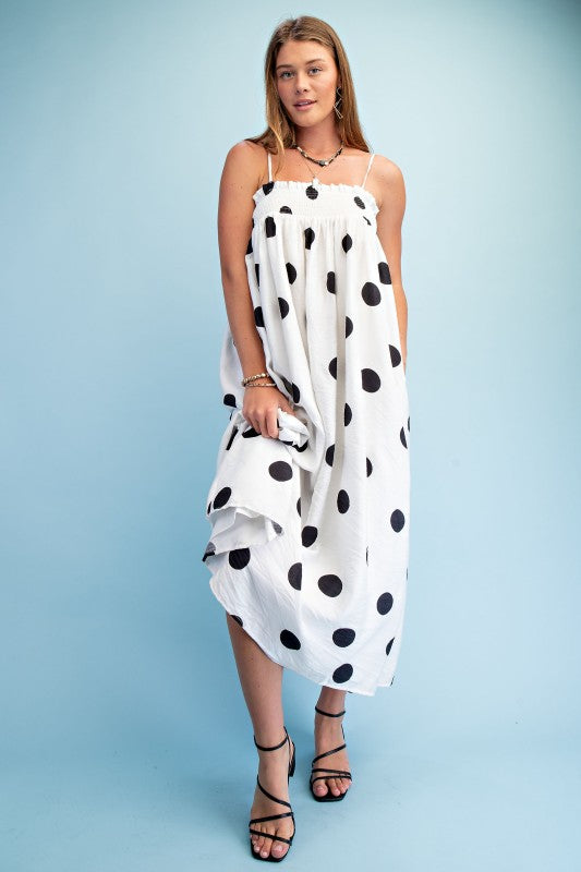 Woman wearing a polka dot smocked maxi dress with adjustable straps styled for summer