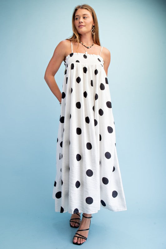 Woman wearing a polka dot smocked maxi dress with adjustable straps styled for summer