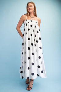 Woman wearing a polka dot smocked maxi dress with adjustable straps styled for summer
