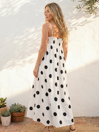 Woman wearing a polka dot smocked maxi dress with adjustable straps styled for summer