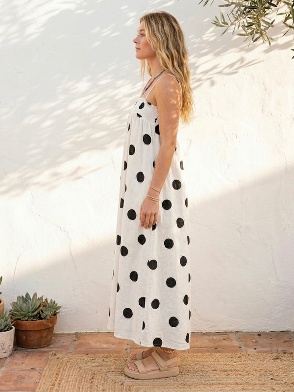 Woman wearing a polka dot smocked maxi dress with adjustable straps styled for summer