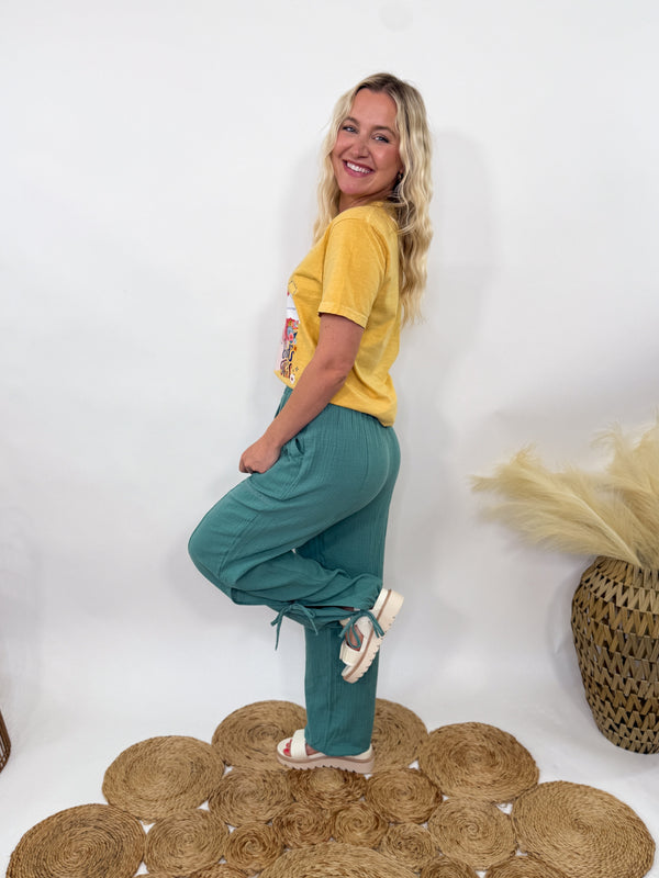 Sage green boho harem jogger pants with lace trim and adjustable side ties, styled with graphic tee