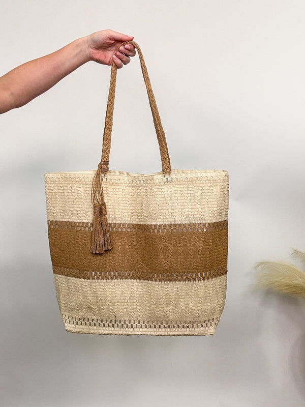 Two-tone woven tote bag with tassel detail, spacious and lightweight, perfect for beach vacations and everyday wear.